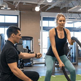 A trainer and client working on battle ropes at Fitness 19